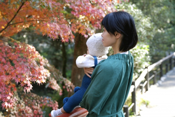 小さい子供を抱いて紅葉を見る女性