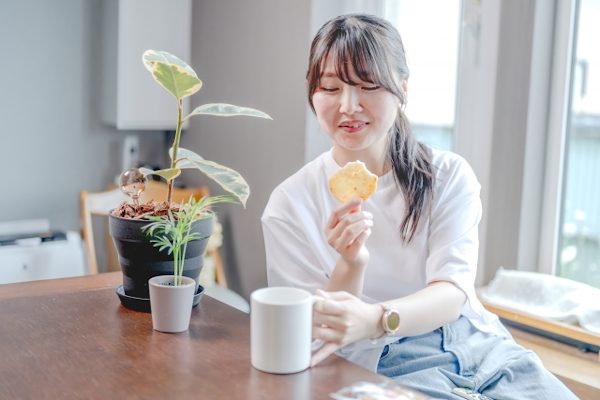 お菓子を食べてコーヒーを飲む女性