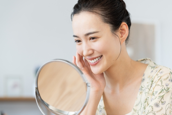鏡を見てほほ笑む女性