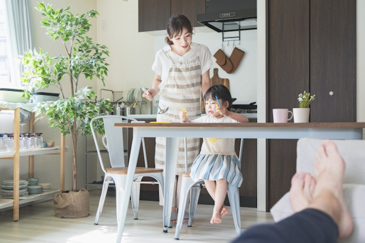 子供の面倒をみながら食事を作る女性