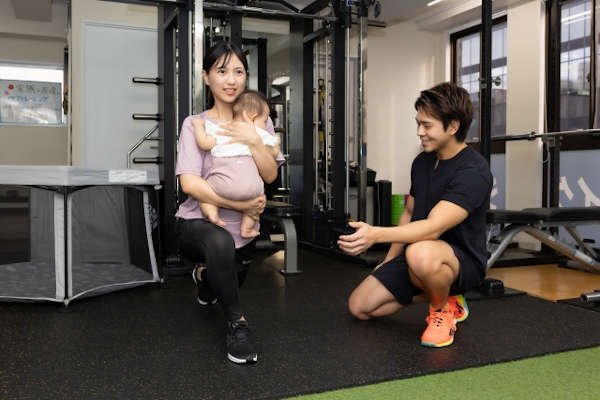 子供を抱いてパーソナルトレーニングを受ける女性