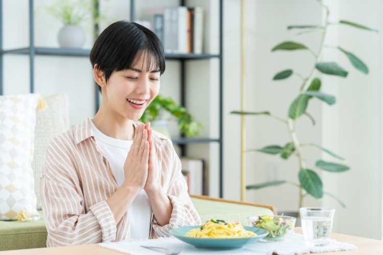 食事を前に手を合わせる女性