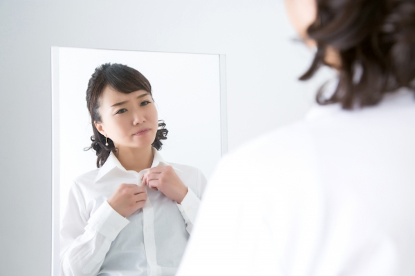 鏡で上半身を気にする女性