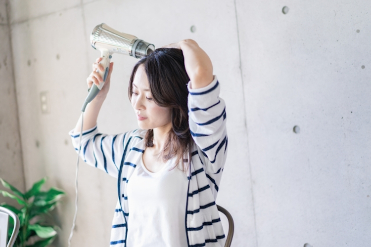 お風呂上りに髪を乾かす女性
