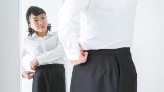 姿見の前で服のサイズを気にする女性