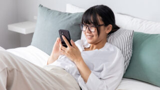 ベットでスマホを操作する女性