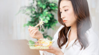 嫌いな物を食べるのを躊躇する女性
