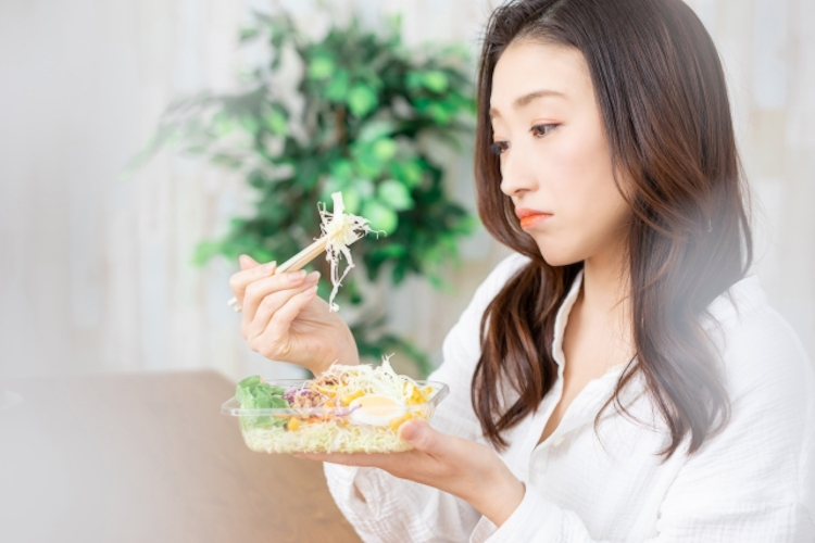 嫌いな物を食べるのを躊躇する女性