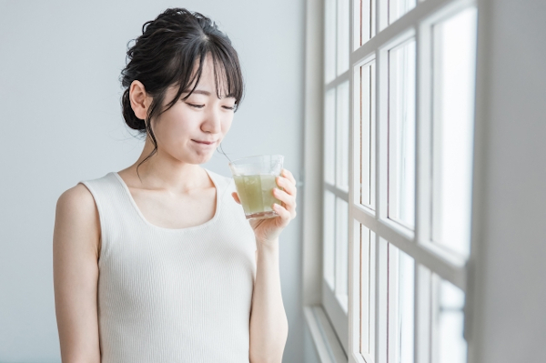 嫌いな味のドリンクを飲もうとする女性