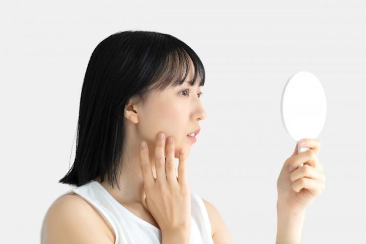 手鏡で顔を気にする女性