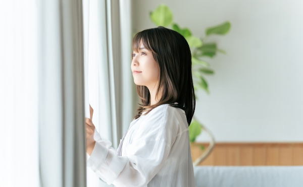 朝窓を開ける女性