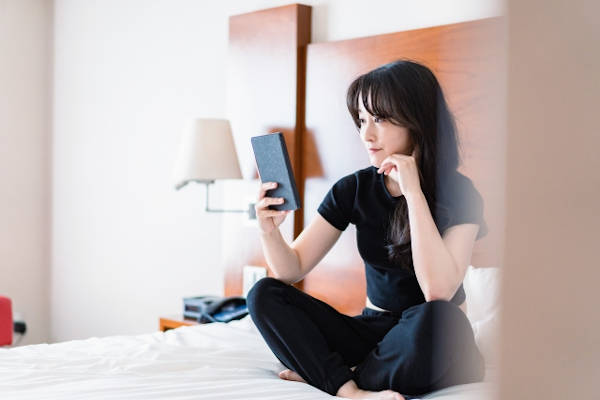 ベットの上でスマホを触る女性